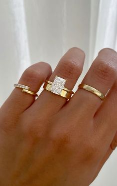 a woman's hand with two gold rings on it and one diamond in the middle