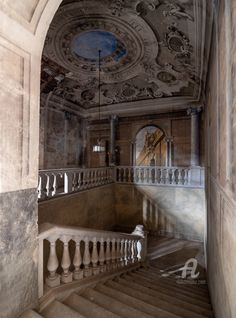 an old building with stairs leading up to the ceiling and a clock on the wall