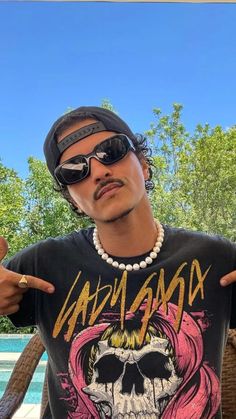 a man wearing sunglasses and a black shirt with a skull on it's chest