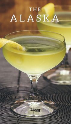 two glasses filled with yellow liquid sitting on top of a table