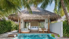 the pool is surrounded by palm trees and lounge chairs, with a thatched roof over it