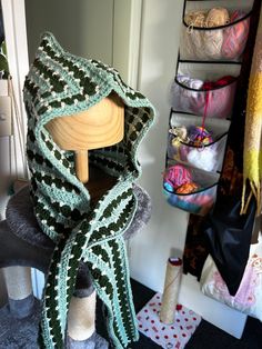 a wooden mannequin with a green and white scarf draped over it's head