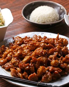 a plate full of chicken and rice with chopsticks next to it on a table