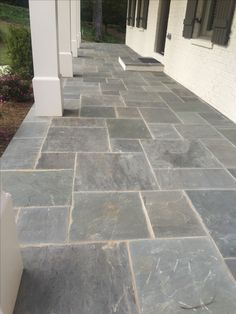 a stone walkway with white pillars and windows