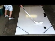 a person is playing with a hockey stick on a table in front of two other people