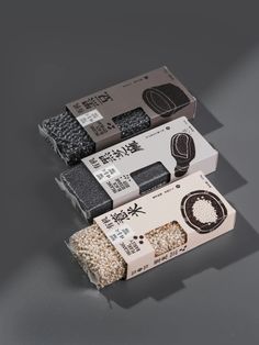 three boxes with different types of rice in them on a gray surface, one is empty and the other two are closed