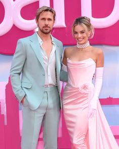 a man and woman standing next to each other on a pink carpet