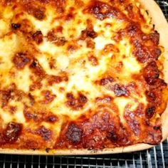 a pizza sitting on top of a metal rack next to a pan filled with cheese