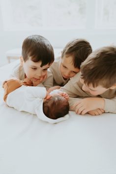 three young boys are playing with a baby