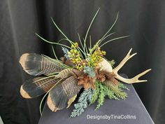 an arrangement of flowers and antlers is displayed on a black tableclothed surface