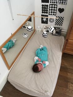 a baby laying on top of a bed next to a mirror