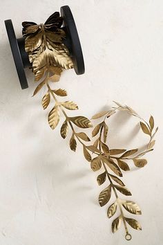 a metal object with gold leaves on it's side hanging from a wall mounted hook