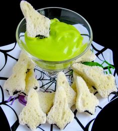 a glass bowl filled with green dip and crackers