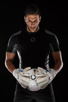 a man holding a soccer ball with his hands on his chest in front of him