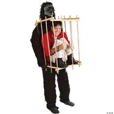 a man dressed in gorilla costume holding a baby and looking through the bars of a cage