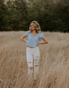 a woman standing in tall grass with her hands on her hips