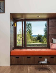 a room with a window and a bench in front of the window that has two pillows on it