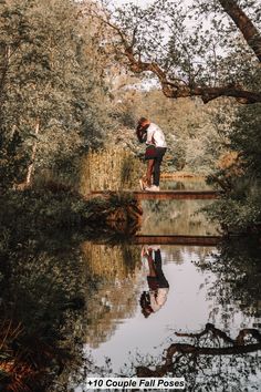 a man is standing on a bridge over a body of water with trees in the background