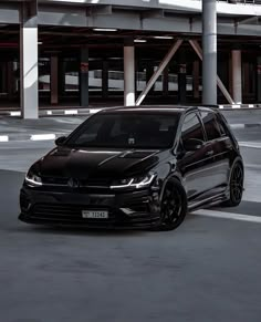 a black volkswagen car is parked in an empty parking lot with no people around it