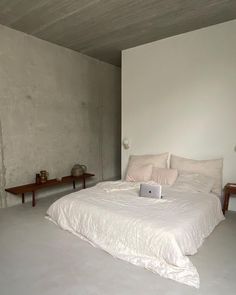 a white bed sitting in a bedroom next to a wooden table and two end tables