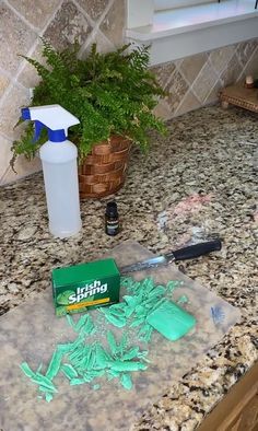 a counter top with green stuff on it and a bottle of cleaner next to it