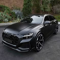 an audi suv parked in a parking lot next to some bushes and trees on the side of the road