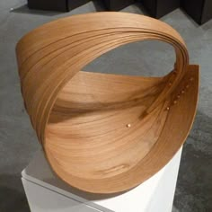 a wooden sculpture sitting on top of a white pedestal