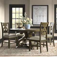 a dining room table with chairs and a vase filled with flowers