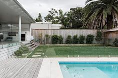 a backyard with a swimming pool and wooden decking next to a fenced in yard