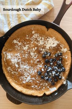 a pancake with powdered sugar and blueberries in it on a wooden table