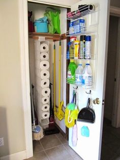 the door is open and there are many cleaning supplies hanging on the wall next to it