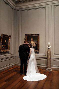 the bride and groom are standing in front of some art on display at the museum