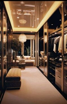 a large walk in closet with lots of clothes on hangers and lights hanging from the ceiling