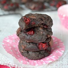 three chocolate cookies stacked on top of each other with cherries in the middle,