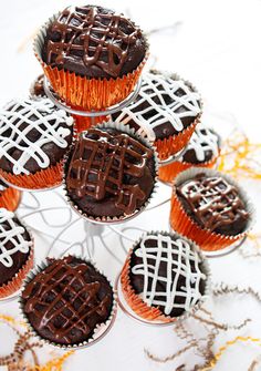 chocolate cupcakes with white icing are arranged in a circle on a cake stand