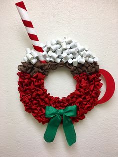 a christmas wreath made out of candy canes and other holiday decorations on a white wall