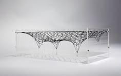 a glass table with an intricate design on the top and bottom, in front of a gray background