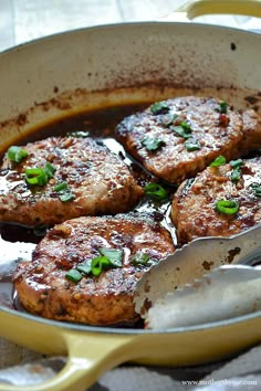 some meat patties are cooking in a skillet with a spoon on the side