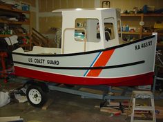 a red and white boat sitting in a garage