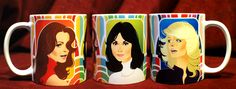 three coffee mugs with the faces of four women painted on them, all in different colors