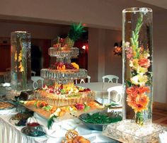 there is a buffet table with many different foods on it and flowers in vases