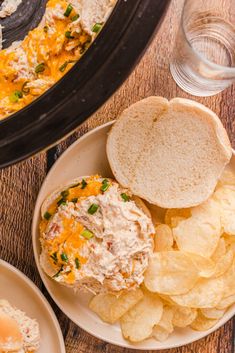 a plate with chips and a sandwich on it next to a crock pot filled with chicken salad