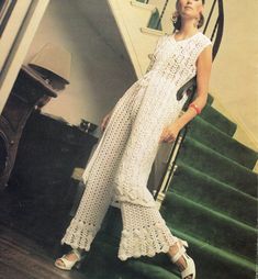 a woman is standing on the stairs in a white crochet dress and sandals