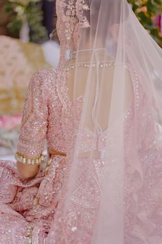 the back of a woman's head wearing a pink bridal gown and veil