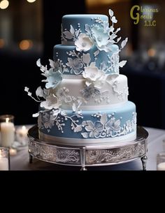 a blue and white wedding cake sitting on top of a silver platter next to candles