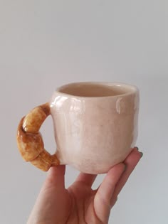 a hand holding a coffee mug with a pretzel in it's middle