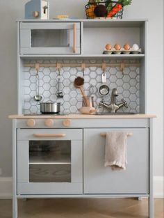 a kitchen with an oven, sink and shelves on the wall above it is also a pot rack that holds utensils