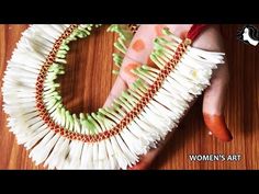 a woman's hand holding a necklace made out of toothpicks