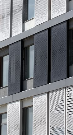 the side of an office building with many windows and perfored screens on it