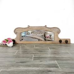 a mirror sitting on top of a wooden floor next to flowers and a vase with pink roses